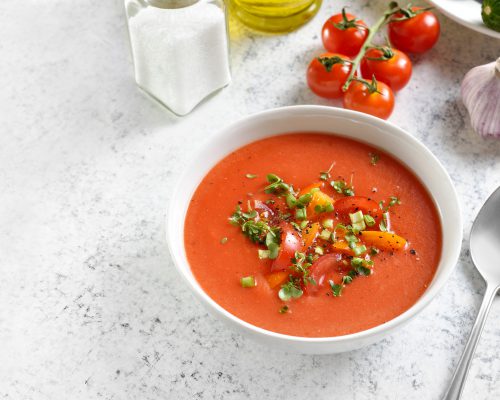 Gazpacho soup in bowl over light stone background with copy space. Cold tomato soup. Close up view