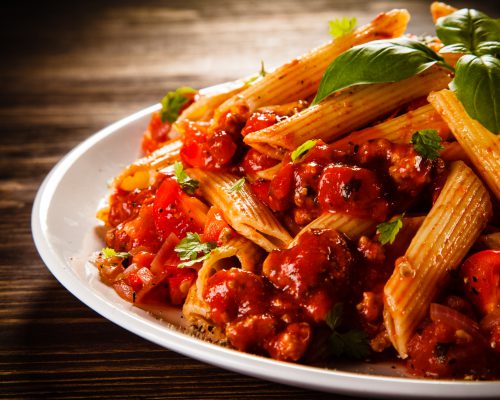 Pasta with meat, tomato sauce and vegetables on white background